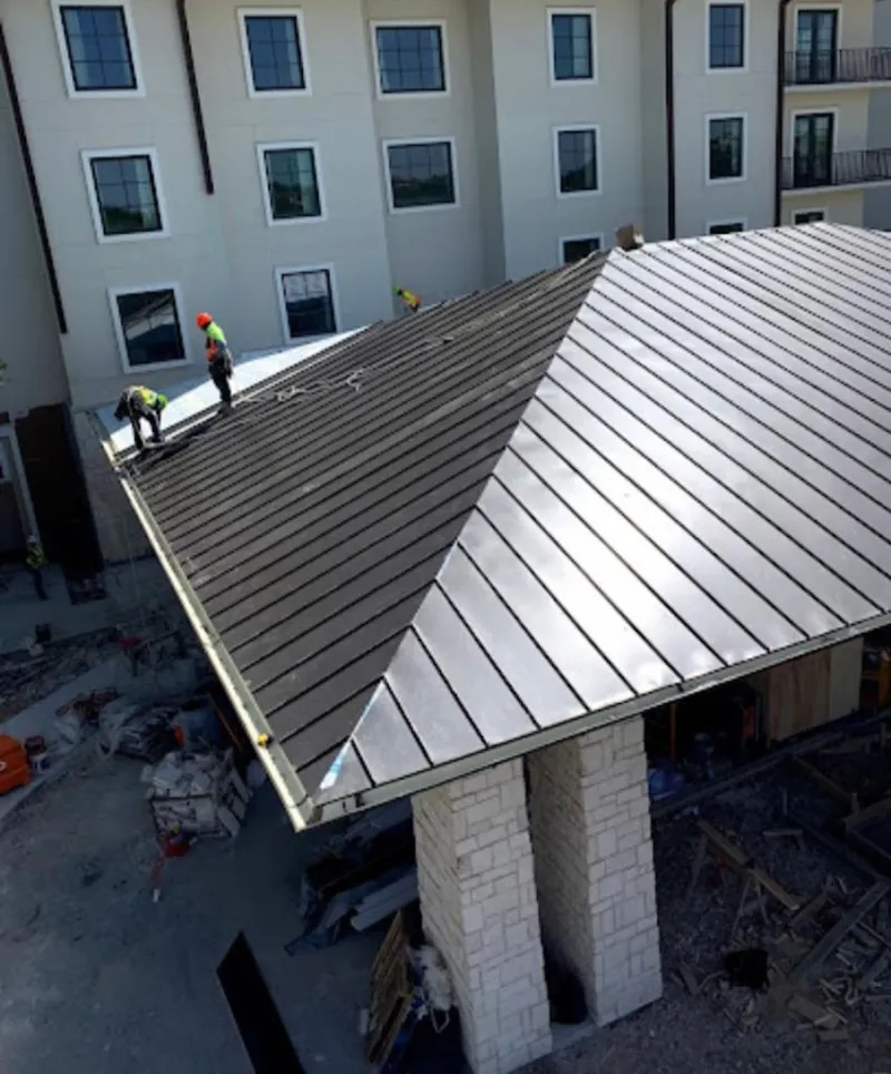 Crew installing standing seam metal roof panels on a commercial project in Potomac